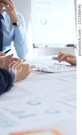 Business team meeting with charts and documents on desk discussing financial strategy, planning corporate growth, analyzing market data and performance reports 132386646