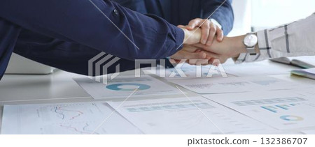 Teamwork and business collaboration with colleagues joining hands over financial charts, symbolizing unity, partnership, success, and strategic corporate planning Teamwork and business collaboration with colleagues joining hands over financial charts, symbolizing unity, partnership, success, and strategic corporate planning 132386707