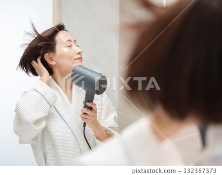 A woman using a hair dryer after taking a bath 132387373