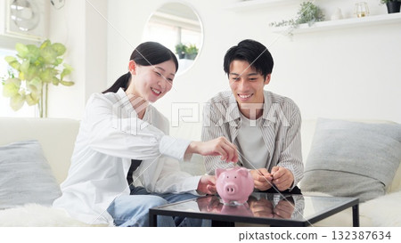 Asian couple putting money into a piggy bank 132387634