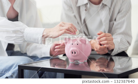 Asian couple putting money into a piggy bank Asian couple putting money into a piggy bank 132387640