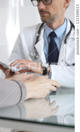 Male doctor consulting female patient, discussing diagnosis and medical history with digital tablet in clinic. Medicine and health care Male doctor consulting female patient, discussing diagnosis and medical history with digital tablet in clinic. Medicine and health care 132388013