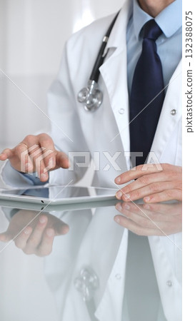 Doctor using digital tablet, consulting with patient, working in healthcare office, telemedicine and medical technology concept. Medicine and health care 132388075
