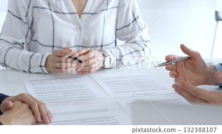 Business professionals or lawyers sitting at the desk in a bright office, reviewing and discussing contract papers. Teamwork concept 132388107