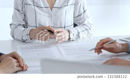 Business professionals or lawyers sitting at the desk in a bright office, reviewing and discussing contract papers. Teamwork concept Business professionals or lawyers sitting at the desk in a bright office, reviewing and discussing contract papers. Teamwork concept 132388112