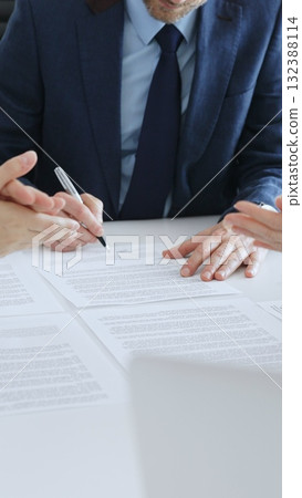 Businessman signing a contract papers at the white desk in office, colleagues applauding to the successful results of negotiations. Business people concept Businessman signing a contract papers at the white desk in office, colleagues applauding to the successful results of negotiations. Business people concept 132388114