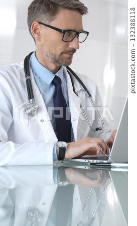 Doctor working on laptop, researching patient data, medical professional analyzing healthcare information in office. Medicine and health care Doctor working on laptop, researching patient data, medical professional analyzing healthcare information in office. Medicine and health care 132388118