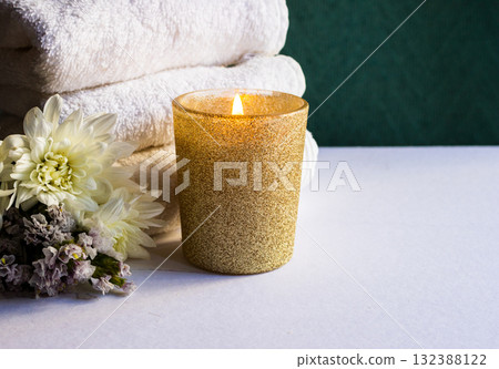 Minimal white spa background with towels, fresh flowers,golden candle and sunlight. Copy space 132388122