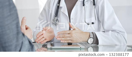 Doctor consulting patient, discussing diagnosis, using digital tablet in modern medical clinic. Medicine and health care 132388177