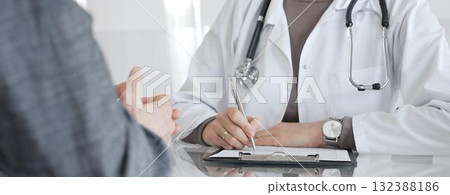 Doctor consulting patient, physician writing medical notes during healthcare examination in modern clinic office. Medicine and health care 132388186