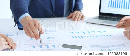 Business people collaborating at a conference table, reviewing financial charts and reports, using a laptop and calculator while engaging in discussions about strategy and performance. Accouters at Business people collaborating at a conference table, reviewing financial charts and reports, using a laptop and calculator while engaging in discussions about strategy and performance. Accouters at 132388196