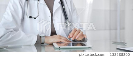 Doctor using digital tablet for medical consultation, viewing health records in modern hospital clinic setting. Medicine and health care Doctor using digital tablet for medical consultation, viewing health records in modern hospital clinic setting. Medicine and health care 132388200