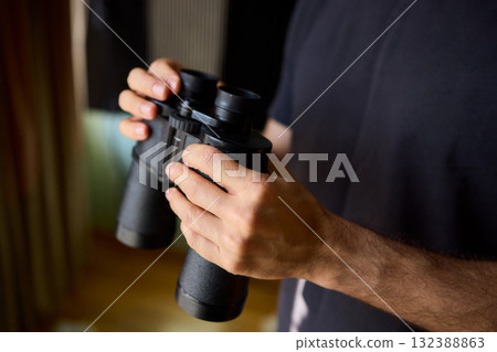 A person using binoculars to observe their surroundings with great focus and detail 132388863