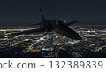 Military Jet Aircraft Flying At Night Over Illuminated City Lights and Dark Sky 132389839