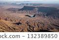 Aerial View Of A Jet Fighter Flying Over The Arid Desert Landscape with Rocky Canyons And Plateaus 132389850