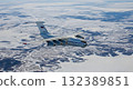 Aerial View Of A White Airplane Flying Over A Snowy Landscape Under Blue Sky 132389851