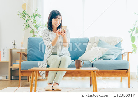 在客廳裡使用智能手機的年輕女子 132390017