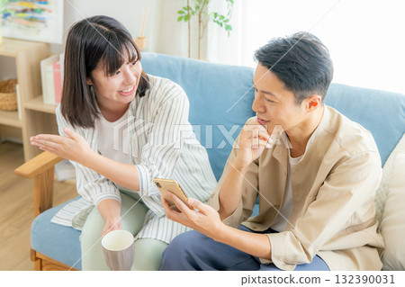 A couple looking at a smartphone in the living room A couple looking at a smartphone in the living room 132390031