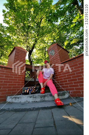 A person resting on a bench under an old, weathered brick archway, with a vintage hanging lantern in the foreground. 132391110