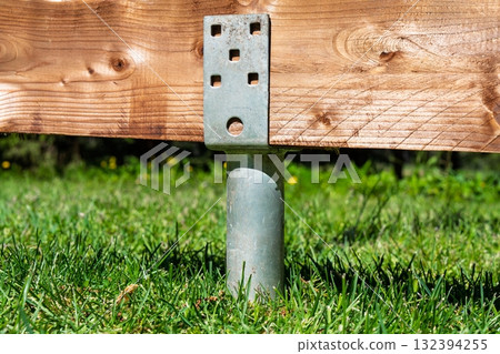 Deck Foundation Support Post Installation with Metal Bracket on Green Grass Lawn 132394255