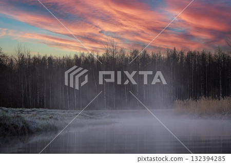 Mystical Sunrise Landscape with Foggy River and Forest Silhouette Under Colorful Sky 132394285