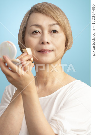 Senior woman putting on makeup Senior woman putting on makeup 132394490