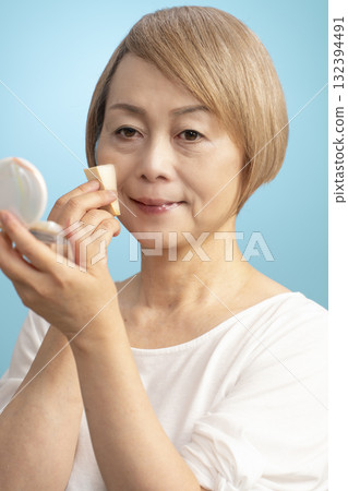Senior woman putting on makeup Senior woman putting on makeup 132394491