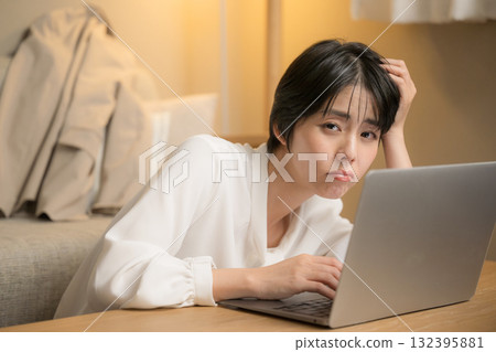 A woman who can't finish her work and ends up working at home. Close-up of a woman holding her head while looking at a computer in a room at night. 132395881
