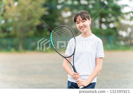 小學、國中和高中女生穿著運動服，在校園或操場上手持網球拍 132395921