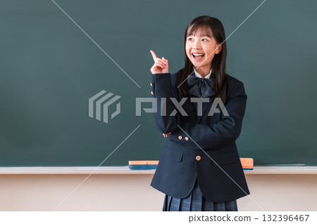 Elementary school, junior high school, and high school girls in blazers standing in front of a blackboard with a smile and coming up with an idea 132396467