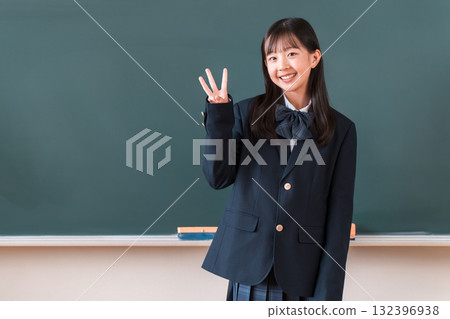 Female elementary, junior high, and high school students in uniforms making the 3 sign in front of the classroom blackboard (countdown) 132396938