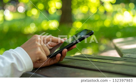 A person operating a tablet in the park A person operating a tablet in the park 132397983