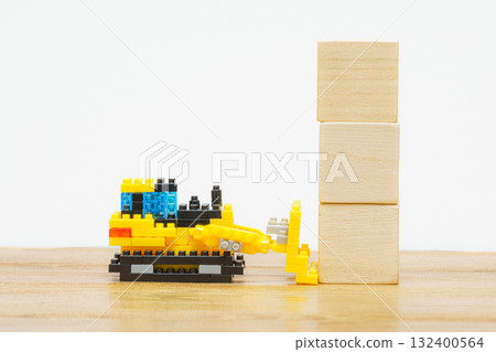 A toy construction scene in which a small bulldozer pushes wooden blocks 132400564