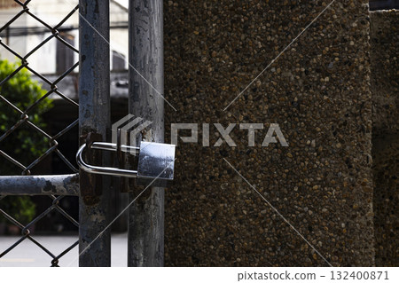 Close up of iron padlock hanging on home gate, strong detail ideal for safety ads, home security campaigns, promotional visuals, and protective lifestyle photography. 132400871