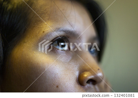 Southeast Asian Woman Gazing At Screen Close Up, A Southeast Asian woman stares intently at a screen, her eyes reflecting soft light, perfect for a focused photo or a digital lifestyle showcase. Southeast Asian Woman Gazing At Screen Close Up, A Southeast Asian woman stares intently at a screen, her eyes reflecting soft light, perfect for a focused photo or a digital lifestyle showcase. 132401081
