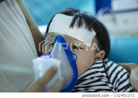Mother Helping Little Son Using Nebulizer During Inhalation, caring home scene perfect for healthcare ads, parenting campaigns, and medical awareness visuals. 132401372