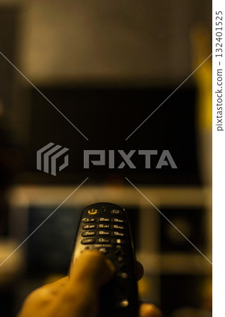 Use the TV remote In Dark Room, authentic home scene designed for electronics marketing, cozy living visuals, and modern lifestyle or leisure content. 132401525