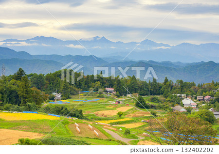 Rural scenery with the Ushiro-Tateyama mountain range towering in the background [Ooka, Nagano City] 132402202