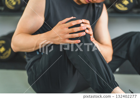 Young Asian man suffering from knee pain while training at the gym Young Asian man suffering from knee pain while training at the gym 132402277