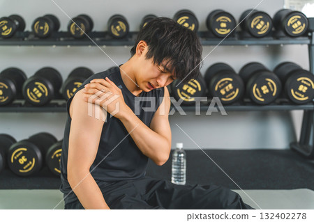 Young Asian man suffering from shoulder pain while training at the gym Young Asian man suffering from shoulder pain while training at the gym 132402278