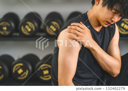 Young Asian man suffering from shoulder pain while training at the gym Young Asian man suffering from shoulder pain while training at the gym 132402279