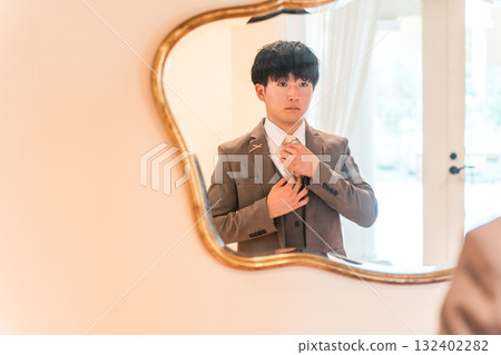 Mirror in the bridal room of a wedding venue, a suit getting ready, and a groom in a tuxedo 132402282