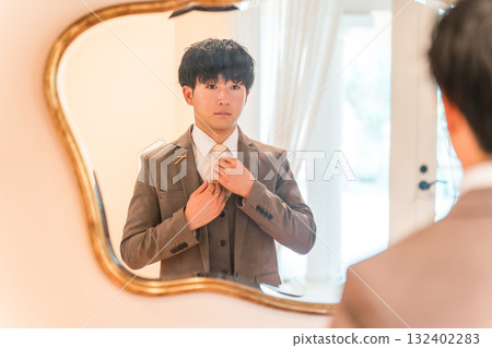 婚禮場地新娘房裡的鏡子、準備的西裝和穿著燕尾服的新郎 132402283