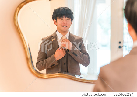 Mirror in the bridal room of a wedding venue, a suit getting ready, and a groom in a tuxedo 132402284