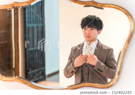 婚禮場地新娘房裡的鏡子、準備的西裝和穿著燕尾服的新郎 132402285