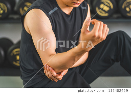 Young Asian man suffering from elbow pain while training at the gym Young Asian man suffering from elbow pain while training at the gym 132402439