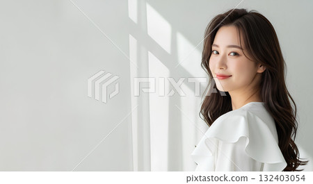 Portrait of a young woman with long hair and white clothes smiling in natural light 132403054