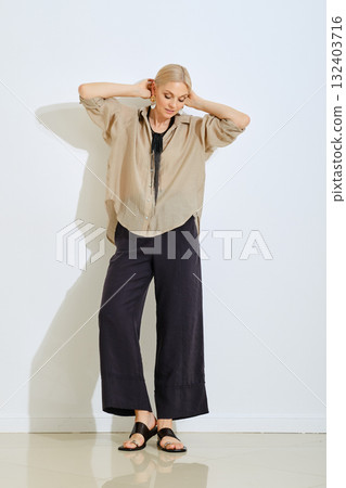 Fashion model poses in casual outfit against a minimalist backdrop in a bright setting Fashion model poses in casual outfit against a minimalist backdrop in a bright setting 132403716