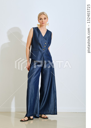 Stylish woman posing in a chic navy outfit during a fashion shoot in a modern studio Stylish woman posing in a chic navy outfit during a fashion shoot in a modern studio 132403725