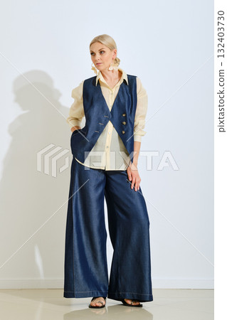 Fashion model showcases stylish denim outfit in a minimalist studio setting during a photoshoot 132403730